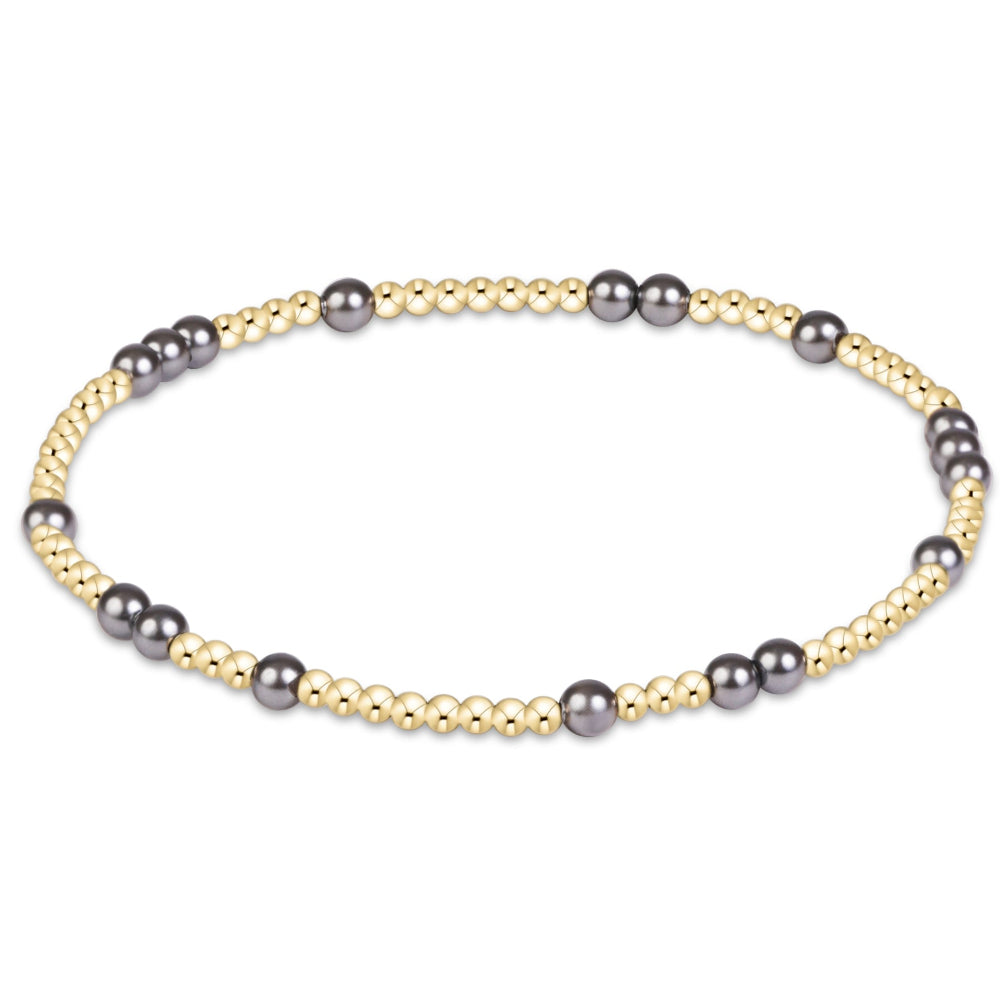 A delicate beaded stretch bracelet featuring alternating strands of gold and dark gray beads, displayed on a clean white background.