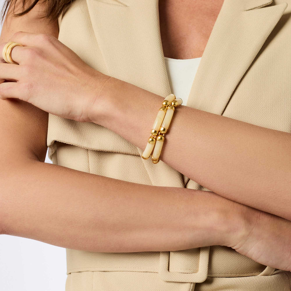 Close-up of a person wearing a gold bracelet with beige suit and white shirt