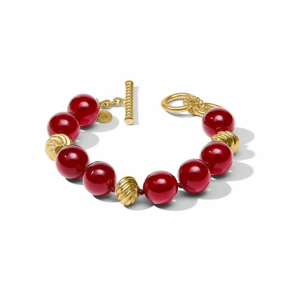 Bracelet with red beads and gold accents on a white background