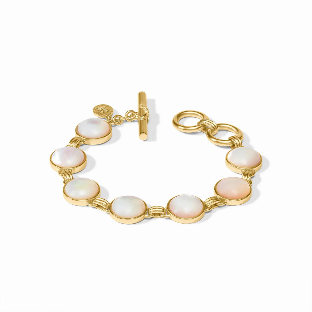 A gold-tone link bracelet featuring seven oval iridescent white mother-of-pearl cabochon stones, complete with a toggle clasp and a small circular logo charm, set against a clean white background.