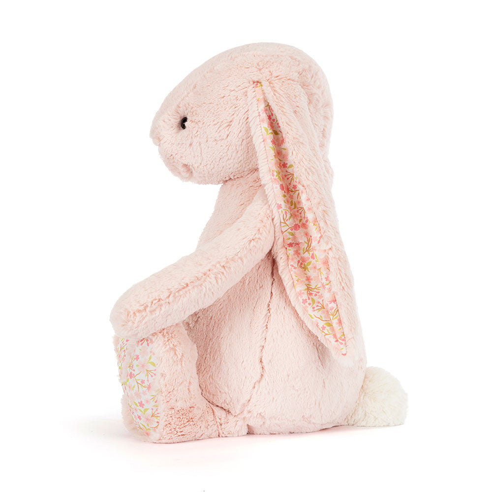 A side  photo of a big sized pink plush bunny with  floral-patterned ears on a white background.