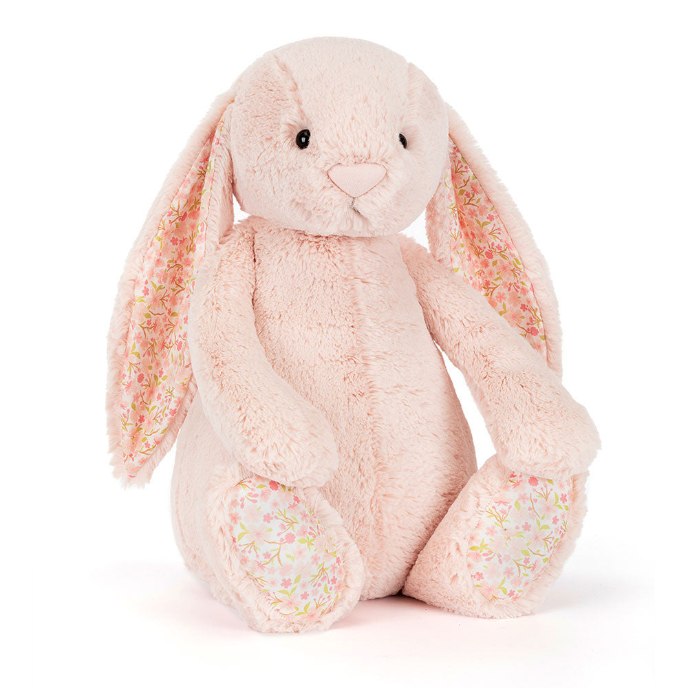 A side angled photo of a big sized pink plush bunny with  floral-patterned ears on a white background.