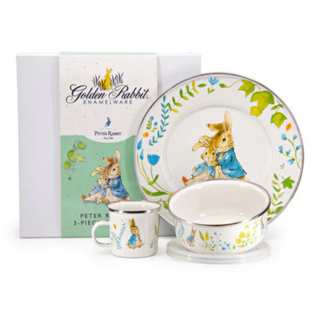 Children's enamelware set with 'Peter Rabbit' design, including a plate, cup, and bowl, with packaging in the background.