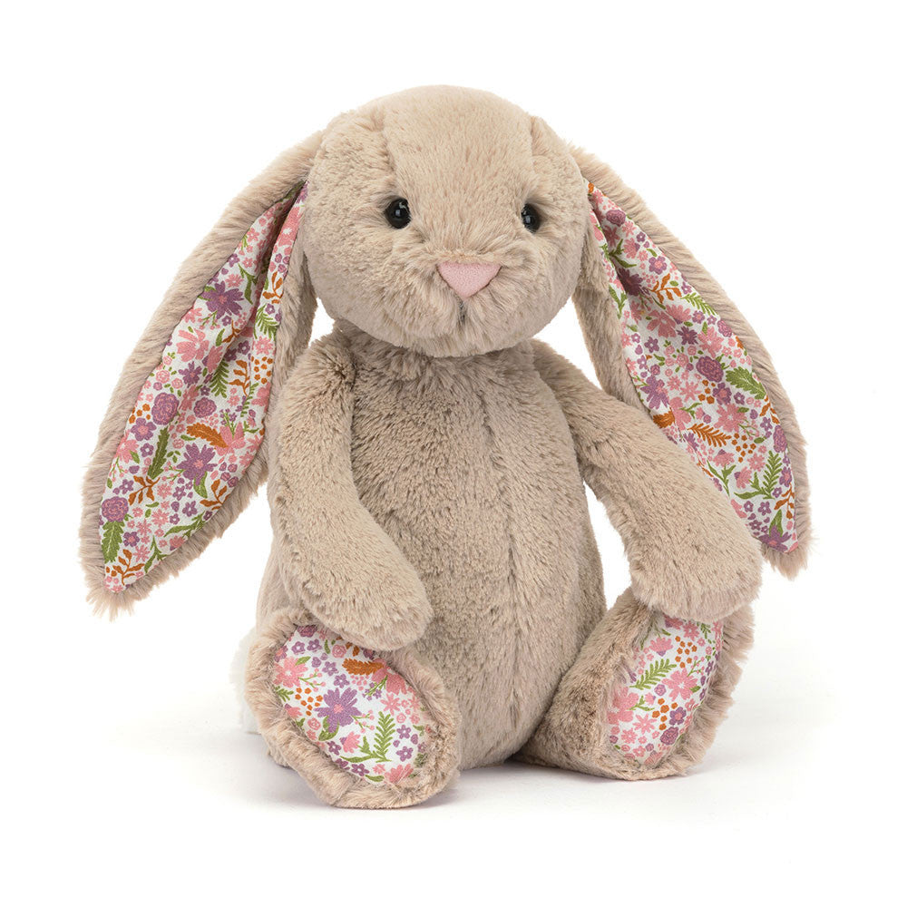 A angled side photo of the original/medium  size beige plush bunny toy with floral patterned ears and feet in a white backround. 