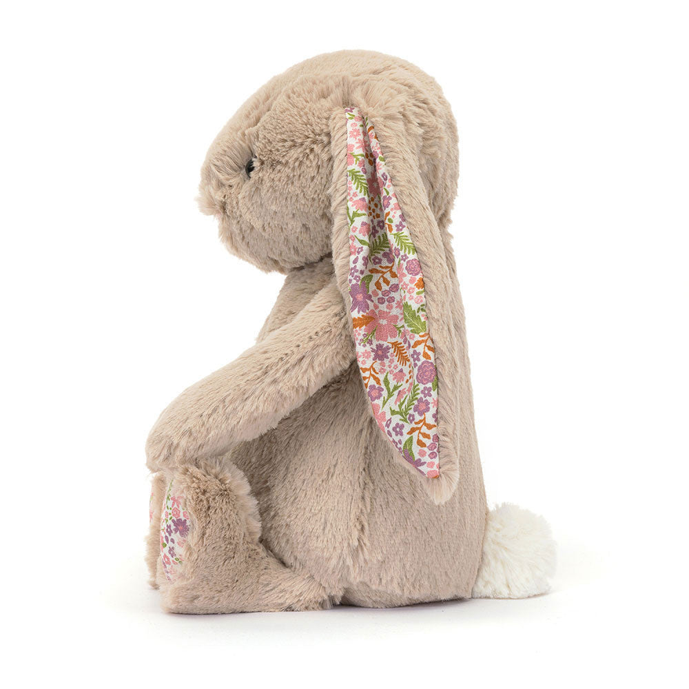 A side photo of the original/medium size beige plush bunny toy with floral patterned ears and feet in a white backround. 