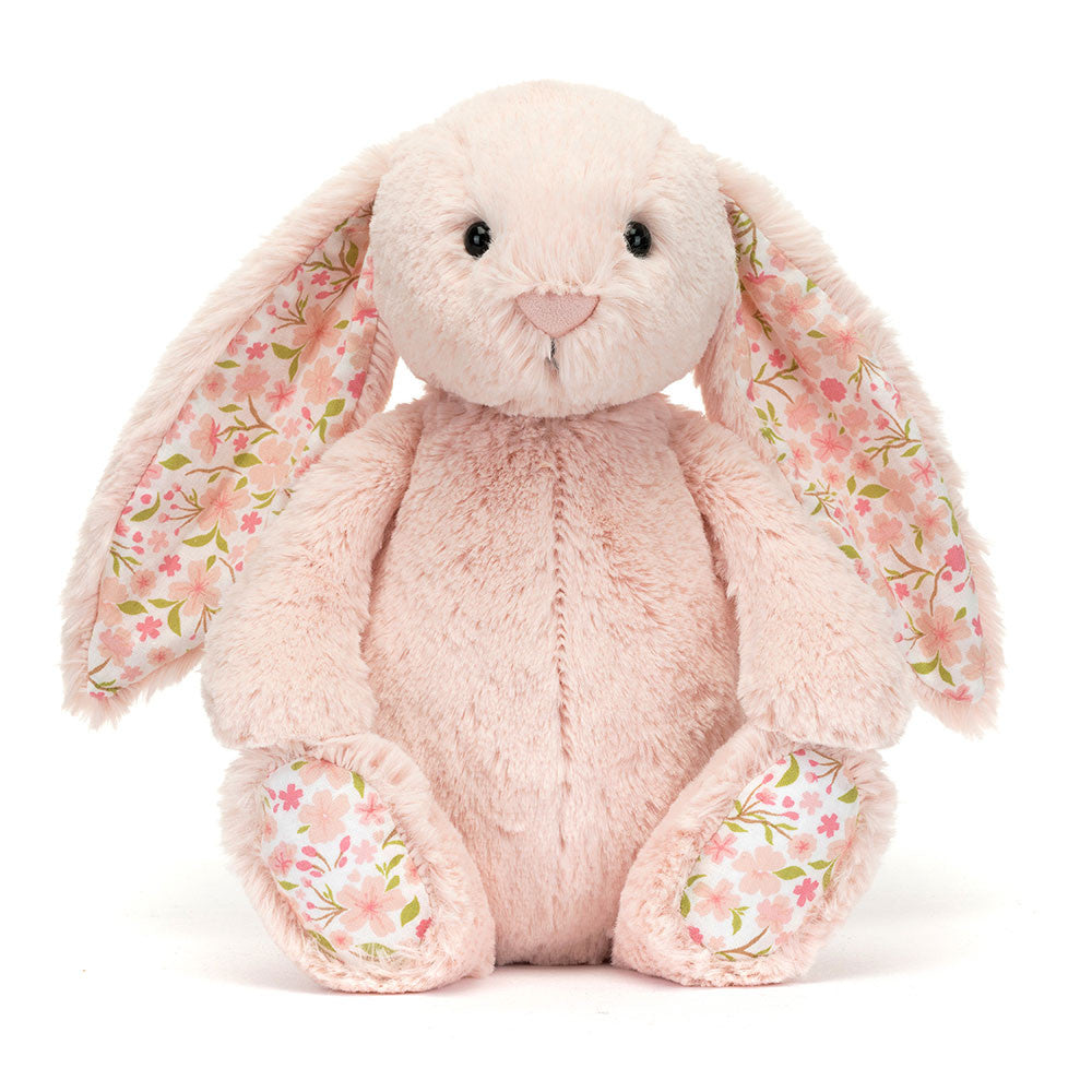 A front photo of a medium/original sized pink plush bunny with  floral-patterned ears on a white background.