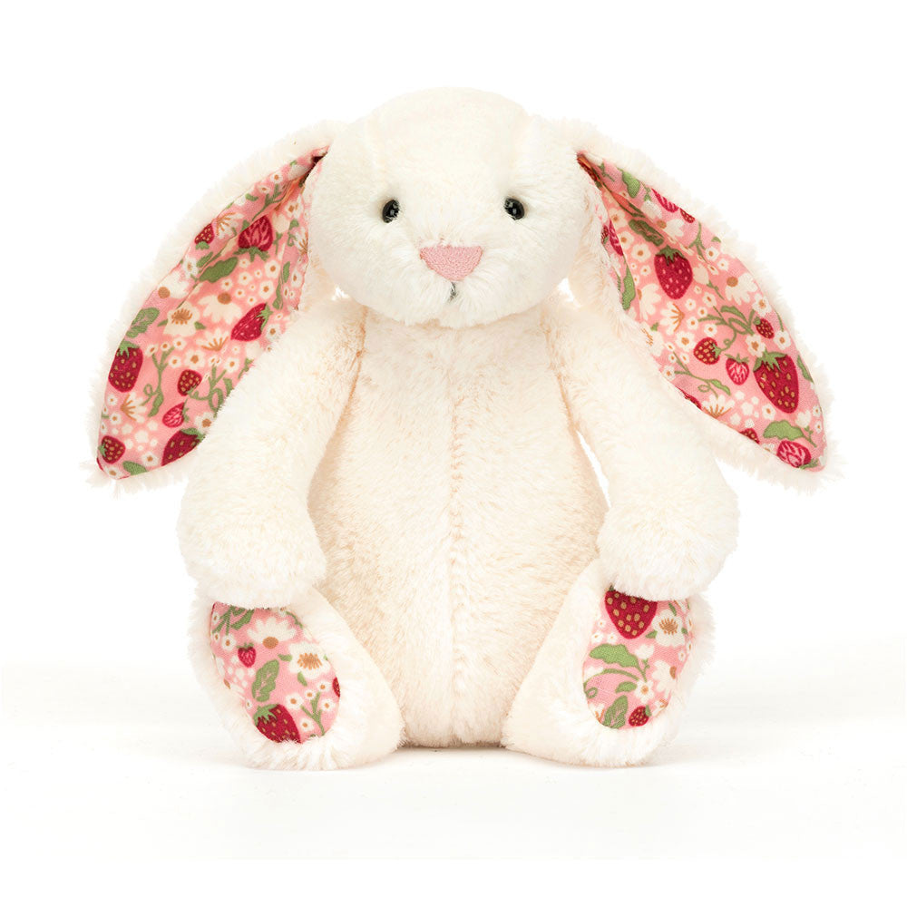 A plush toy depicting a cream-colored bunny with soft cotton ears and feet, featuring a strawberry and cream flower print on a pink background.