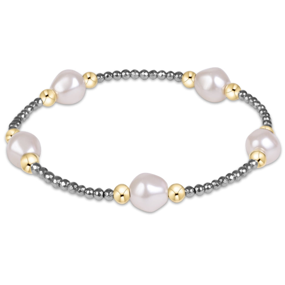 A delicate beaded bracelet featuring large, irregular white baroque pearls and small gold spacer beads set against a dark gray metallic beaded chain, shown on a plain white background.