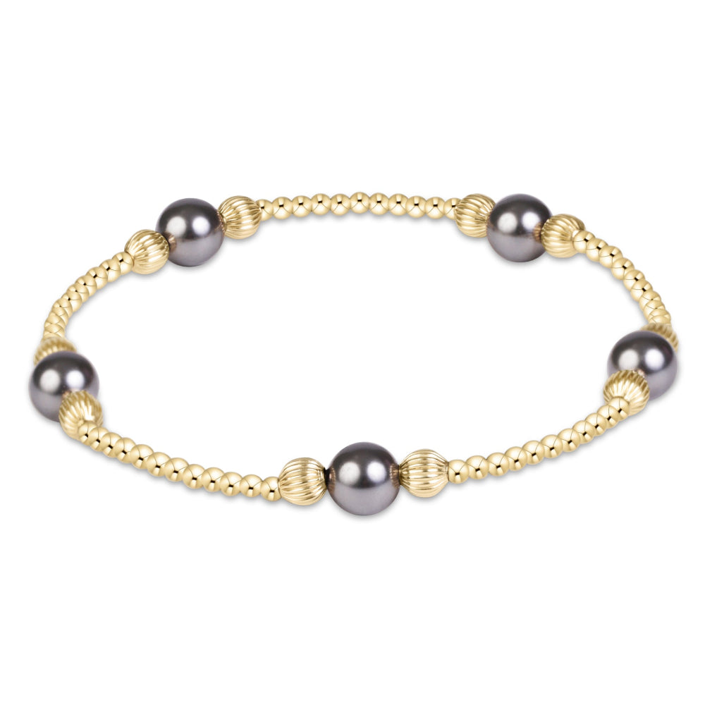 A delicate gold chain bracelet featuring five dark gray freshwater pearls and small gold spacers, displayed on a clean white background.