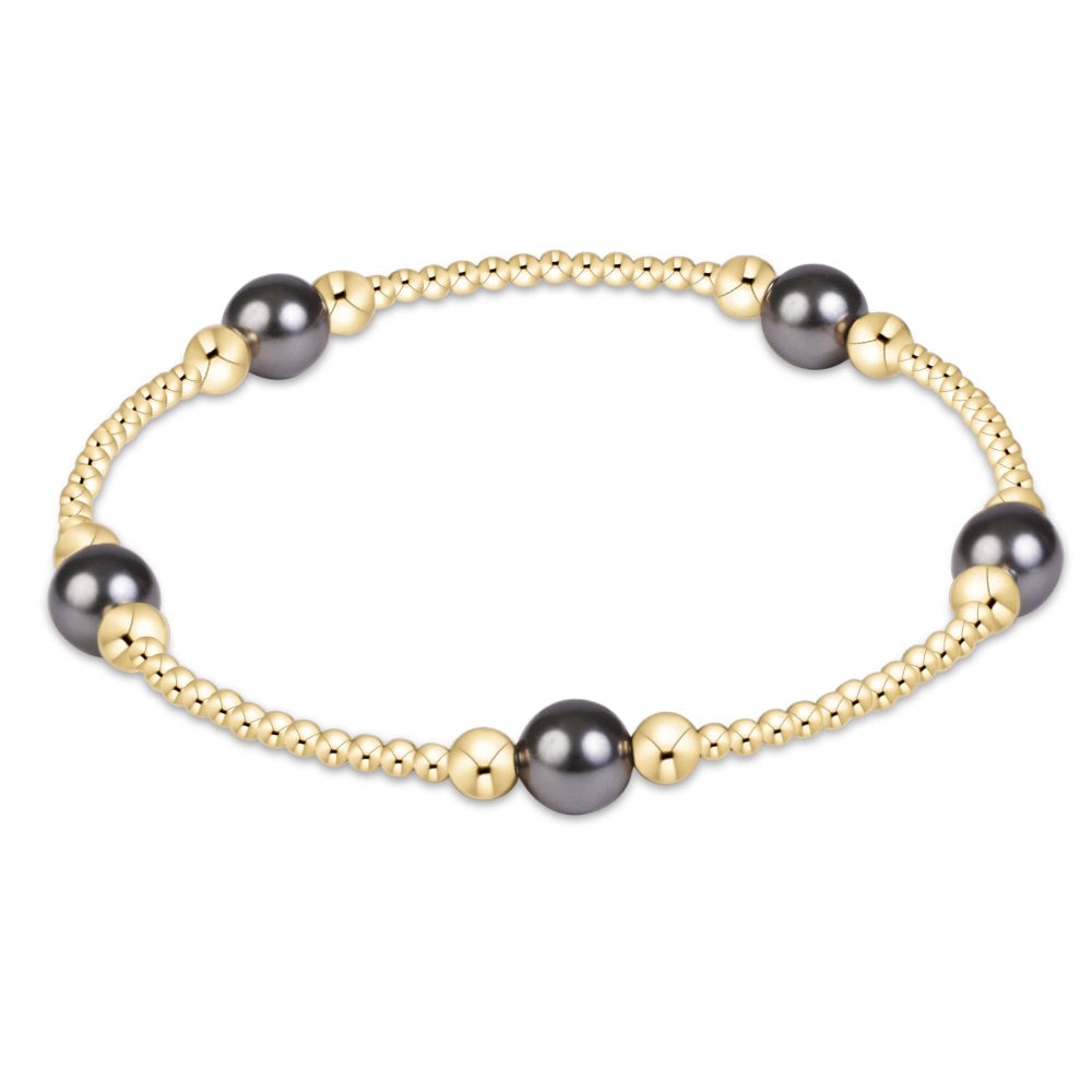 A delicate gold chain bracelet featuring five dark gray freshwater pearl beads spaced evenly, displayed on a clean white background.