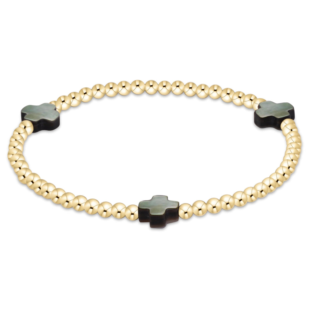 A gold beaded bracelet with three black cross-shaped beads, displayed on a clean white background.