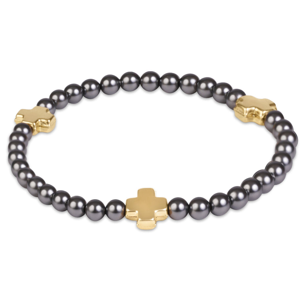 A beaded bracelet featuring dark gray pearls and polished gold-tone cross-shaped charms, displayed on a clean white background.