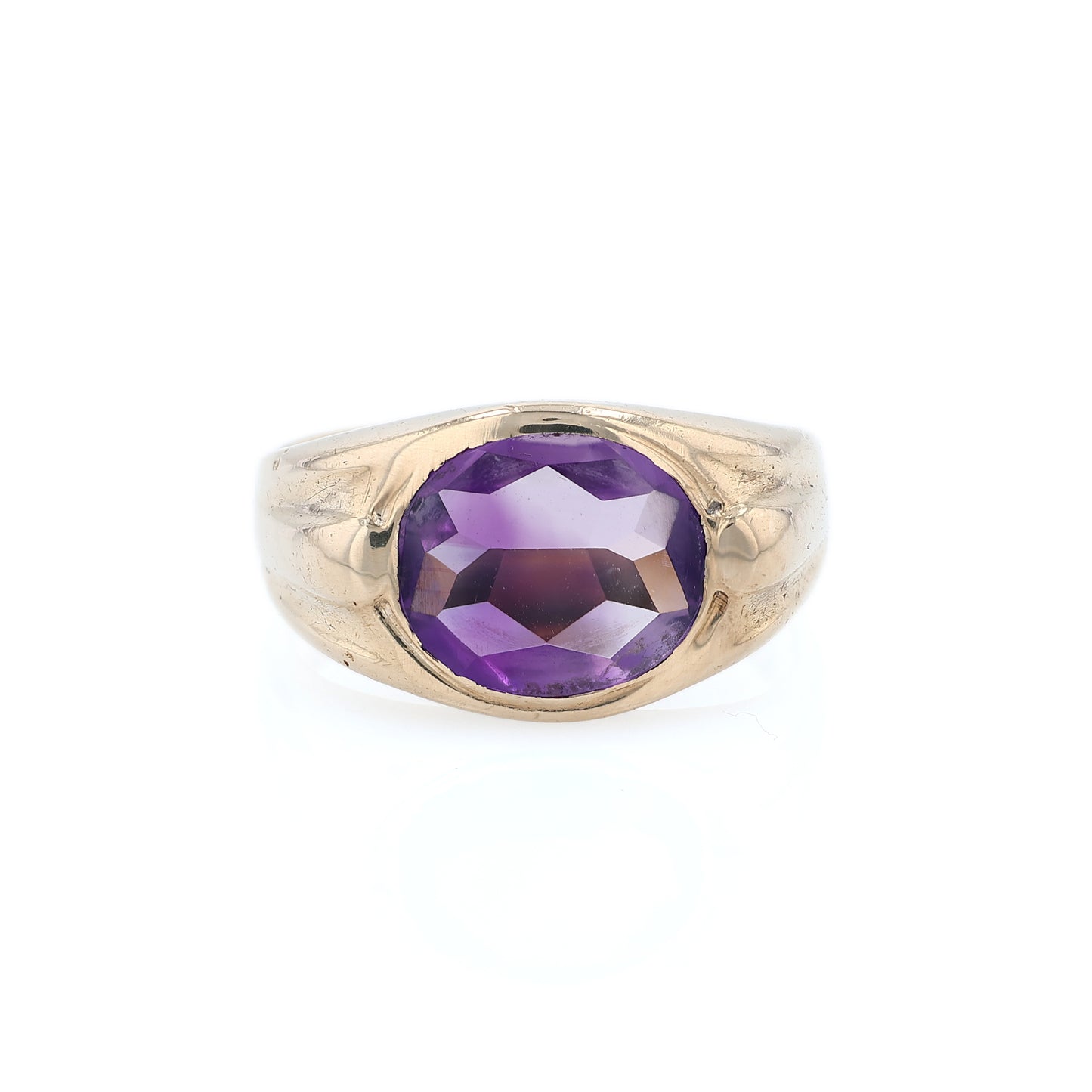 Yellow gold flush bezel set oval amethyst ring on a white background