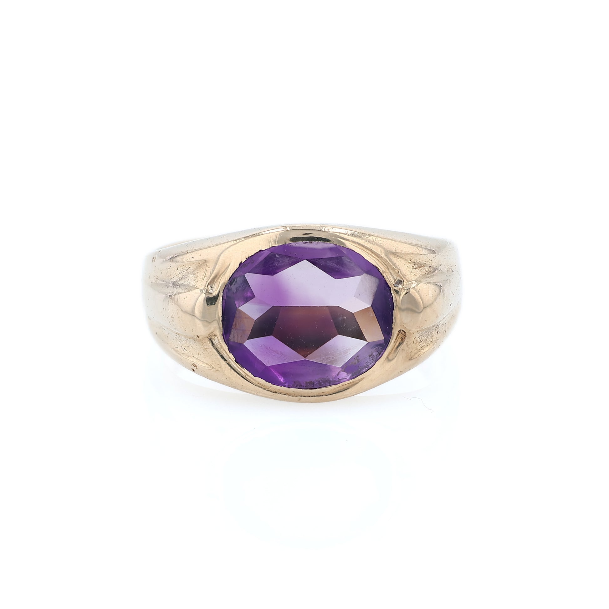 Yellow gold flush bezel set oval amethyst ring on a white background