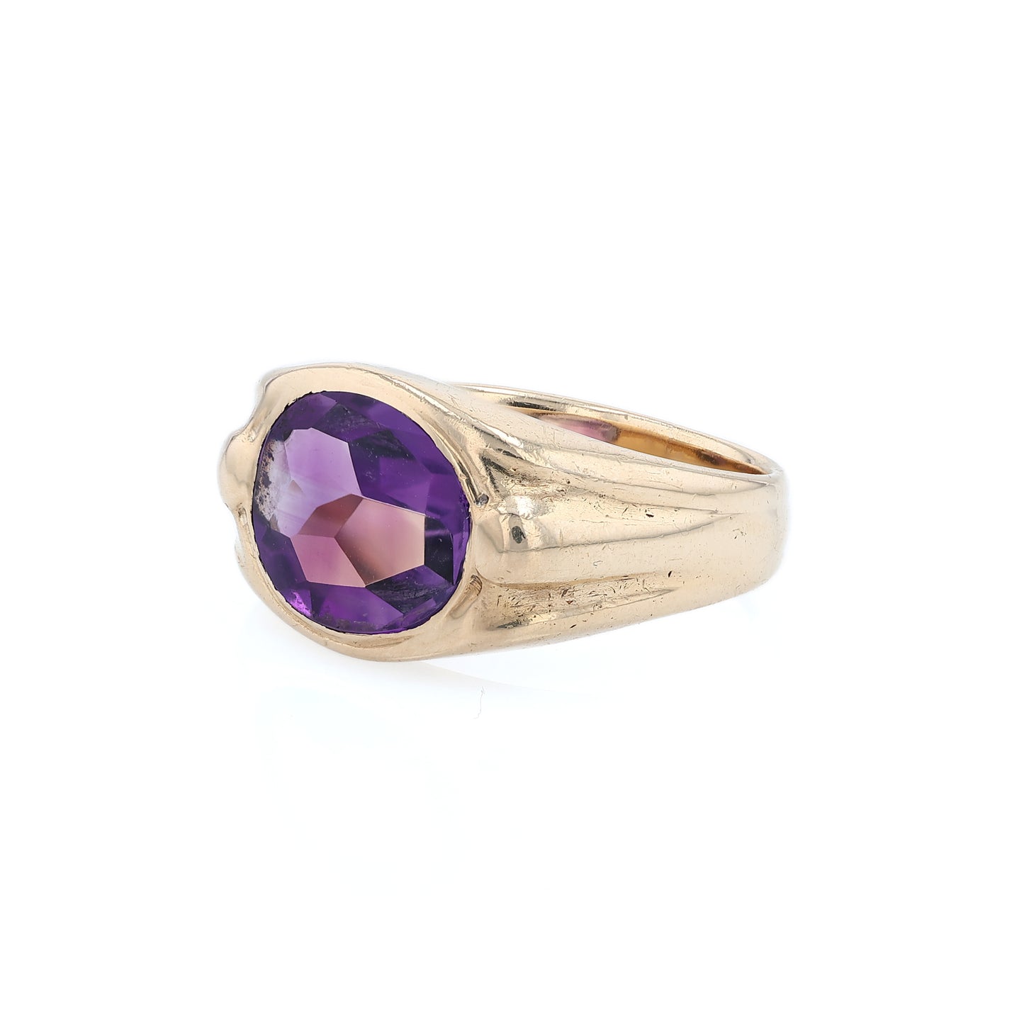 Yellow gold flush bezel set oval amethyst ring on a white background