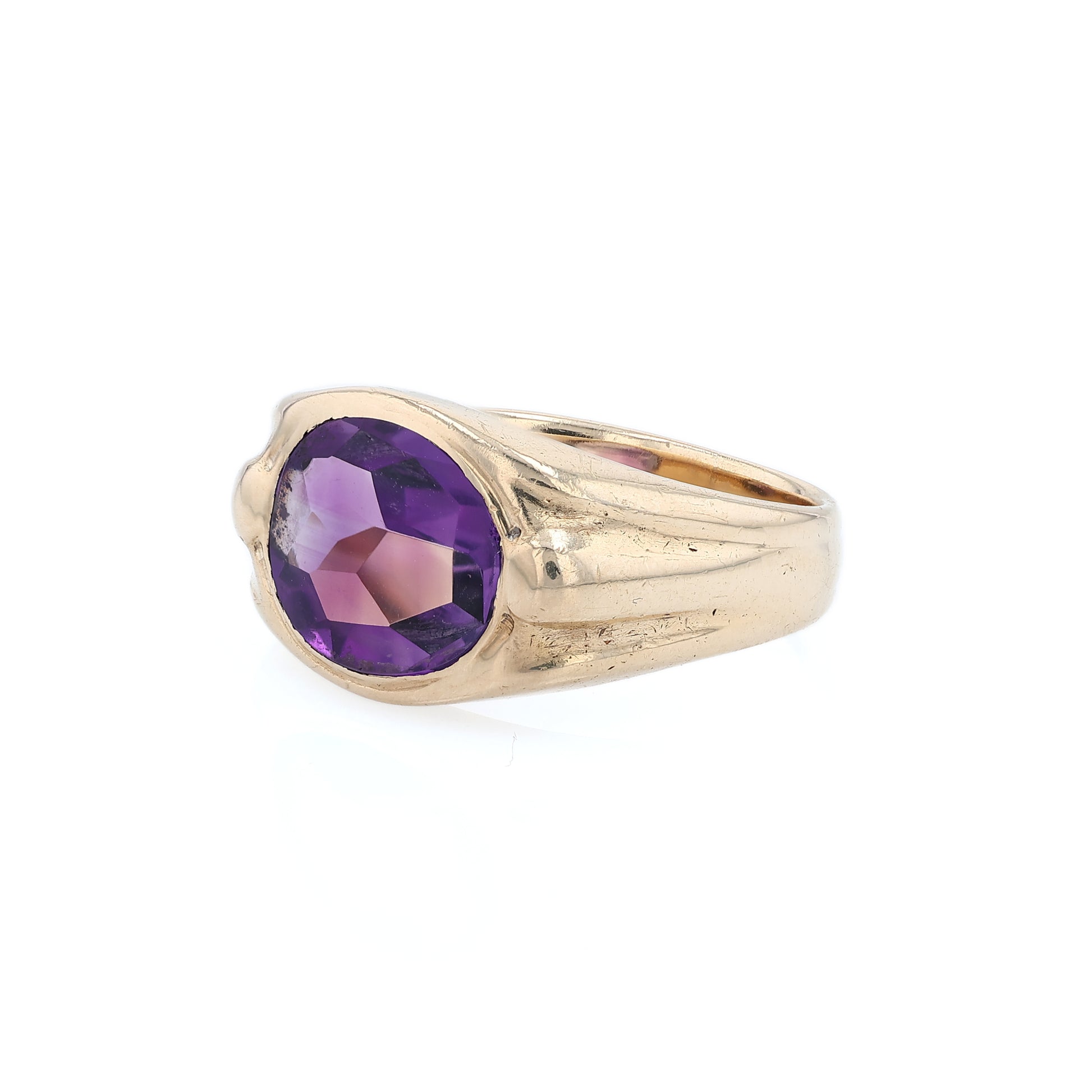 Yellow gold flush bezel set oval amethyst ring on a white background