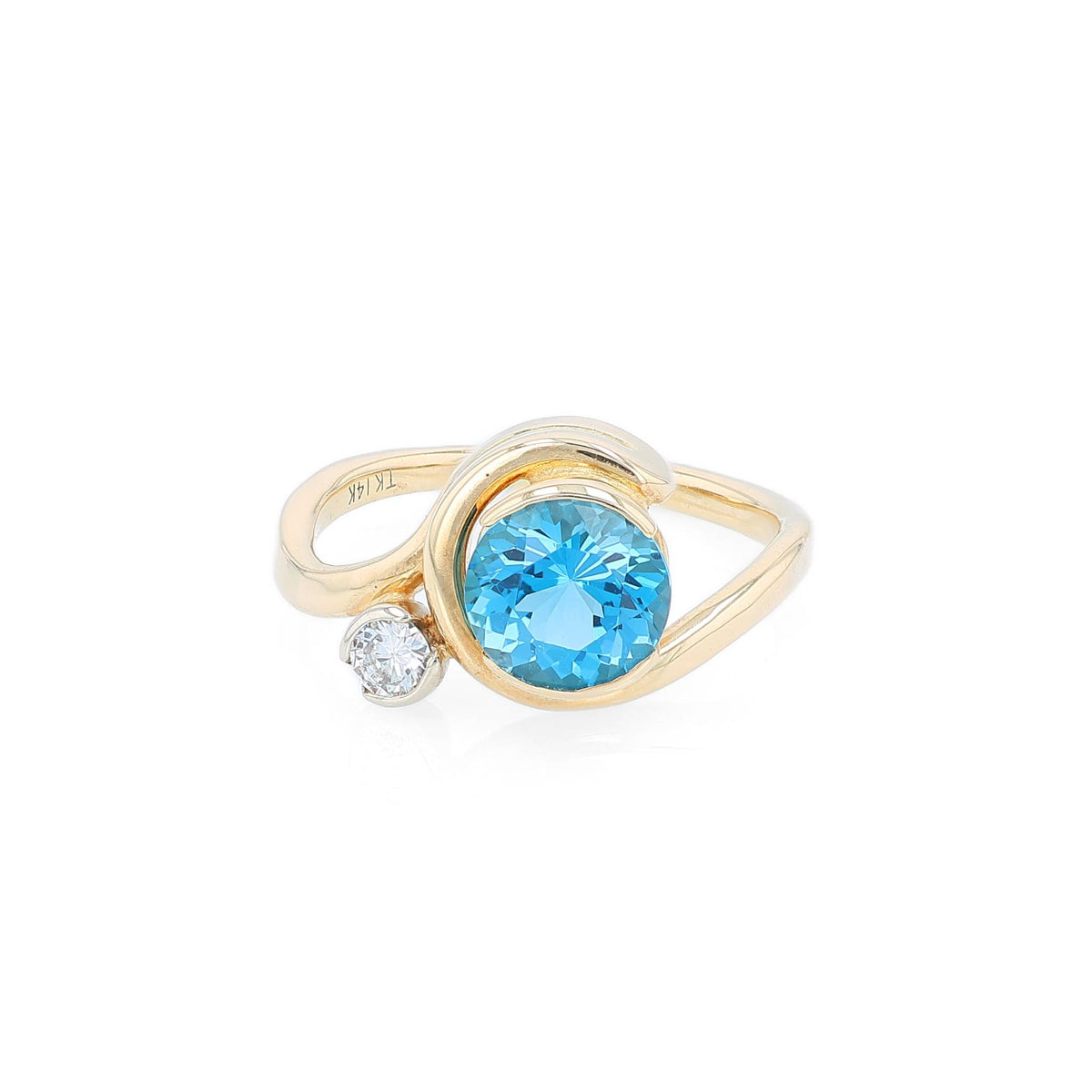 Yellow gold bezel set blue topaz and diamond ring on a white background
