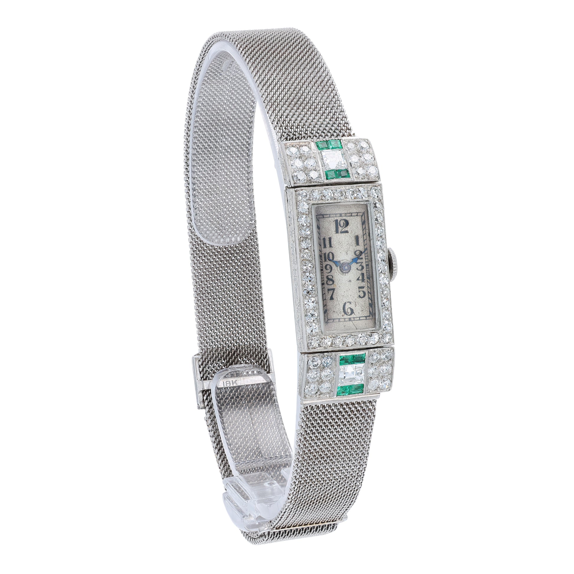 Estate platinum and white gold watch with diamond and emerald accents on case front with an off white dial on a white background