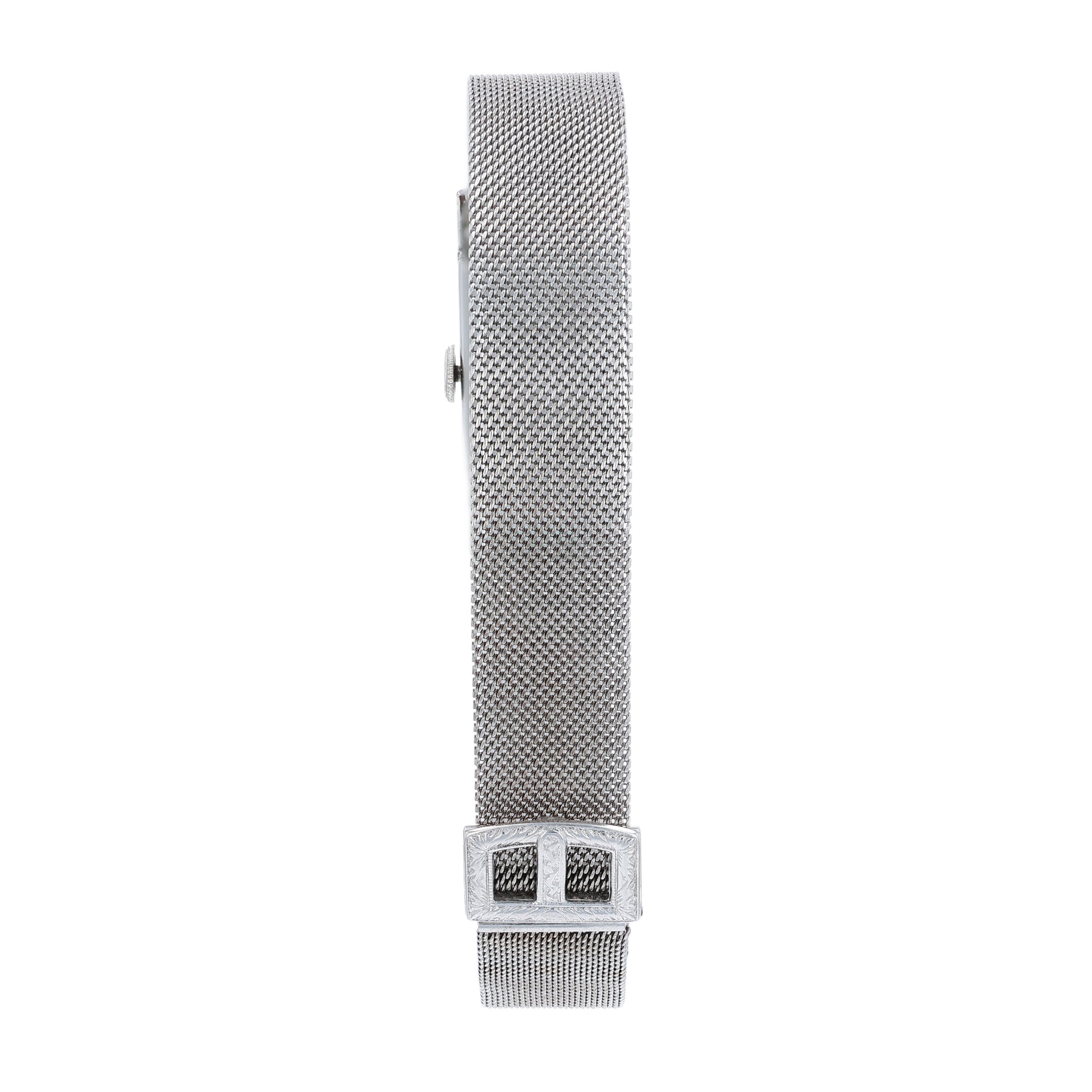 Estate platinum and white gold watch with diamond and emerald accents on case front with an off white dial on a white background