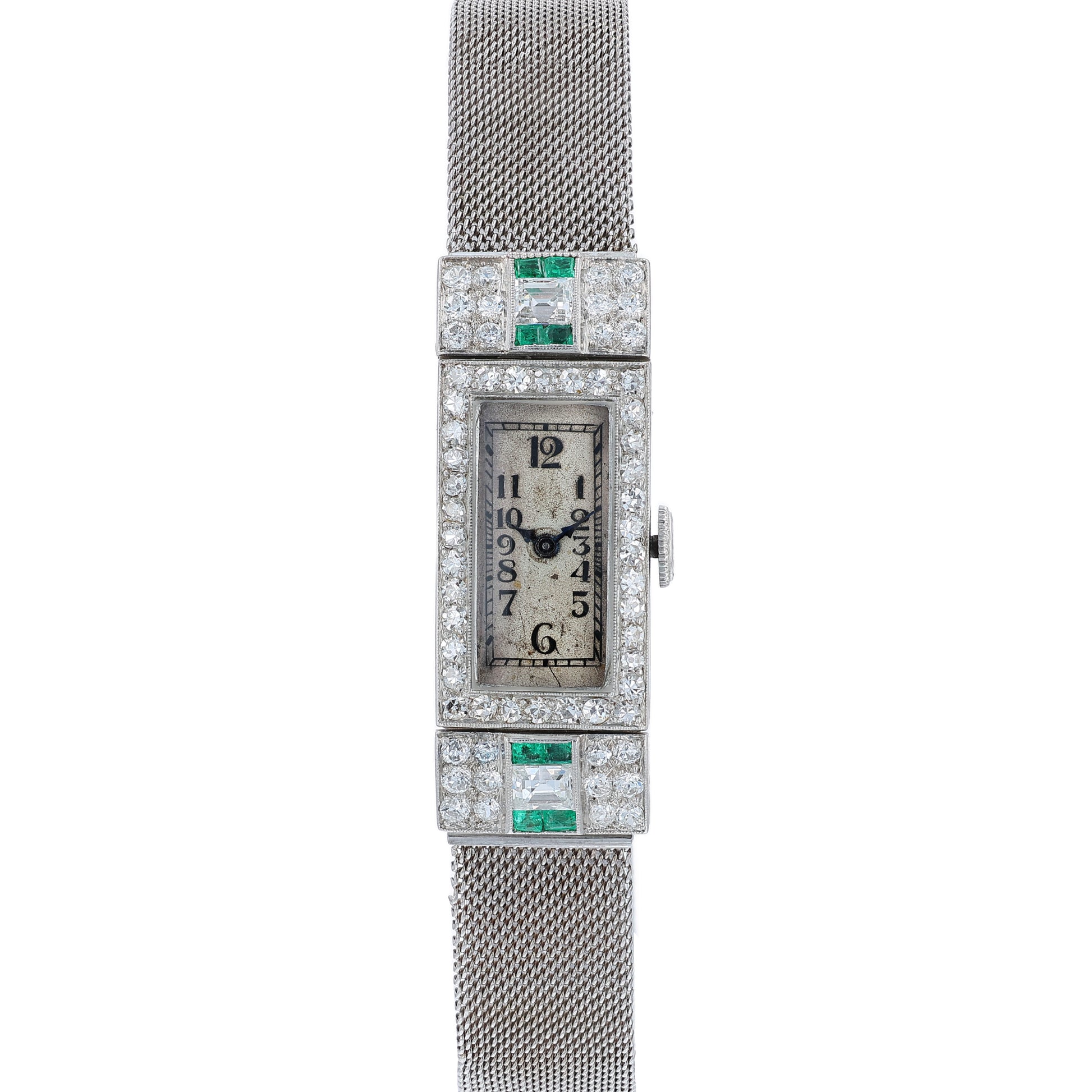 Estate platinum and white gold watch with diamond and emerald accents on case front with an off white dial on a white background