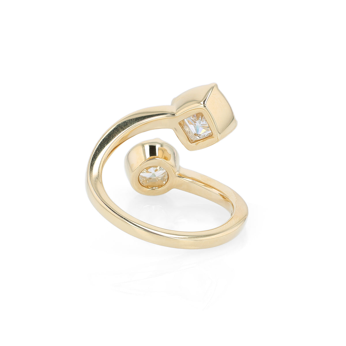 A yellow gold bypass ring featuring diamonds - a princess-cut and a round brilliant-cut diamond - on a clean white background.