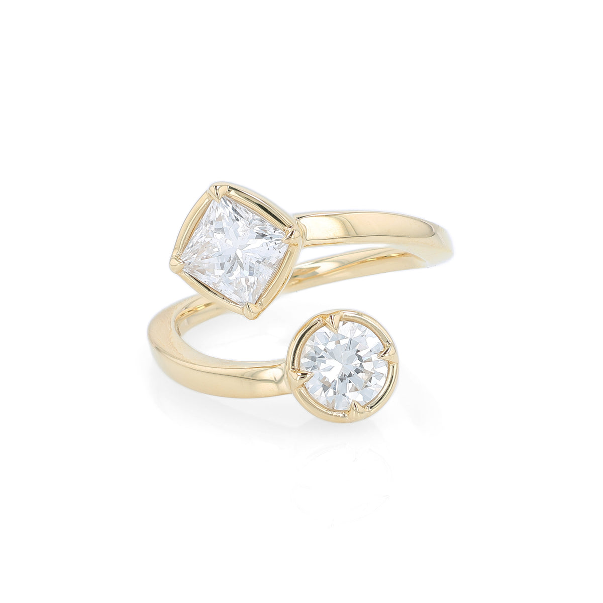 A yellow gold bypass ring featuring diamonds - a princess-cut and a round brilliant-cut diamond - on a clean white background.