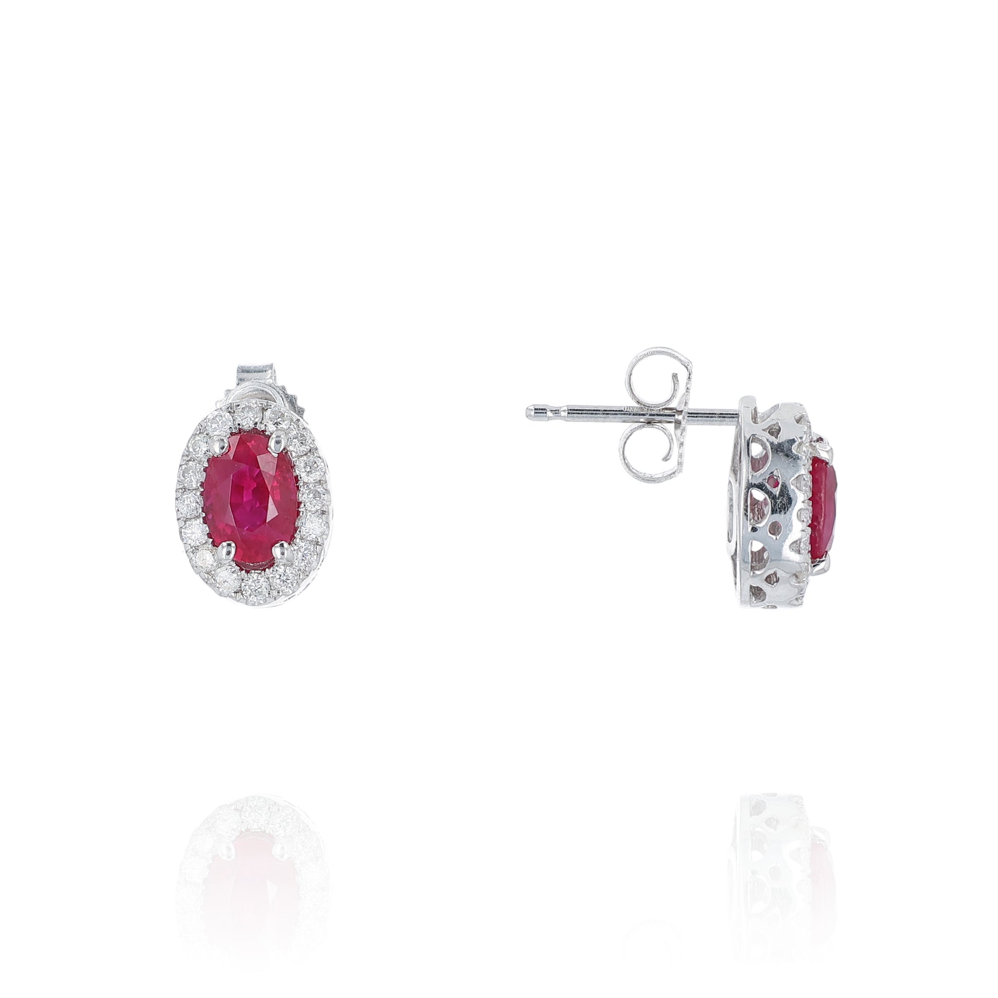 Pair of white gold earrings with oval ruby centers and diamond halos on a white background