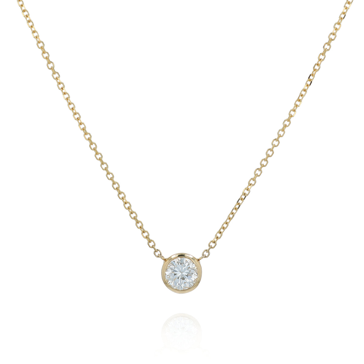 A delicate gold chain necklace with a small bezel-set pendant holding a clear round-cut diamond, displayed against a solid white background.