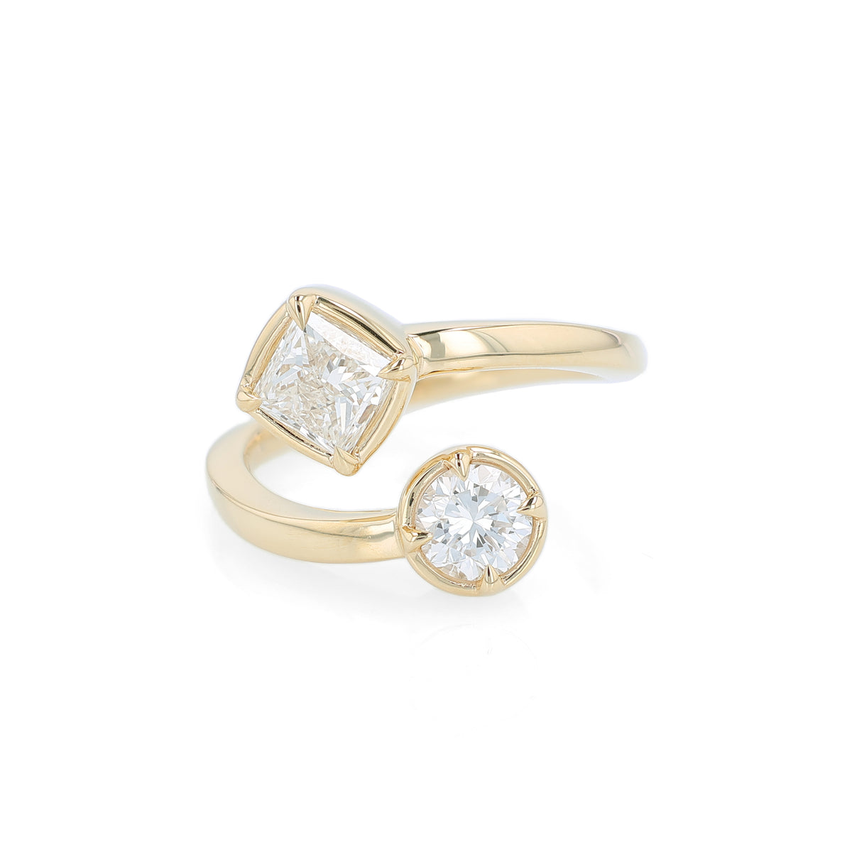 A yellow gold bypass ring featuring diamonds - a princess-cut and a round brilliant-cut diamond - on a clean white background.