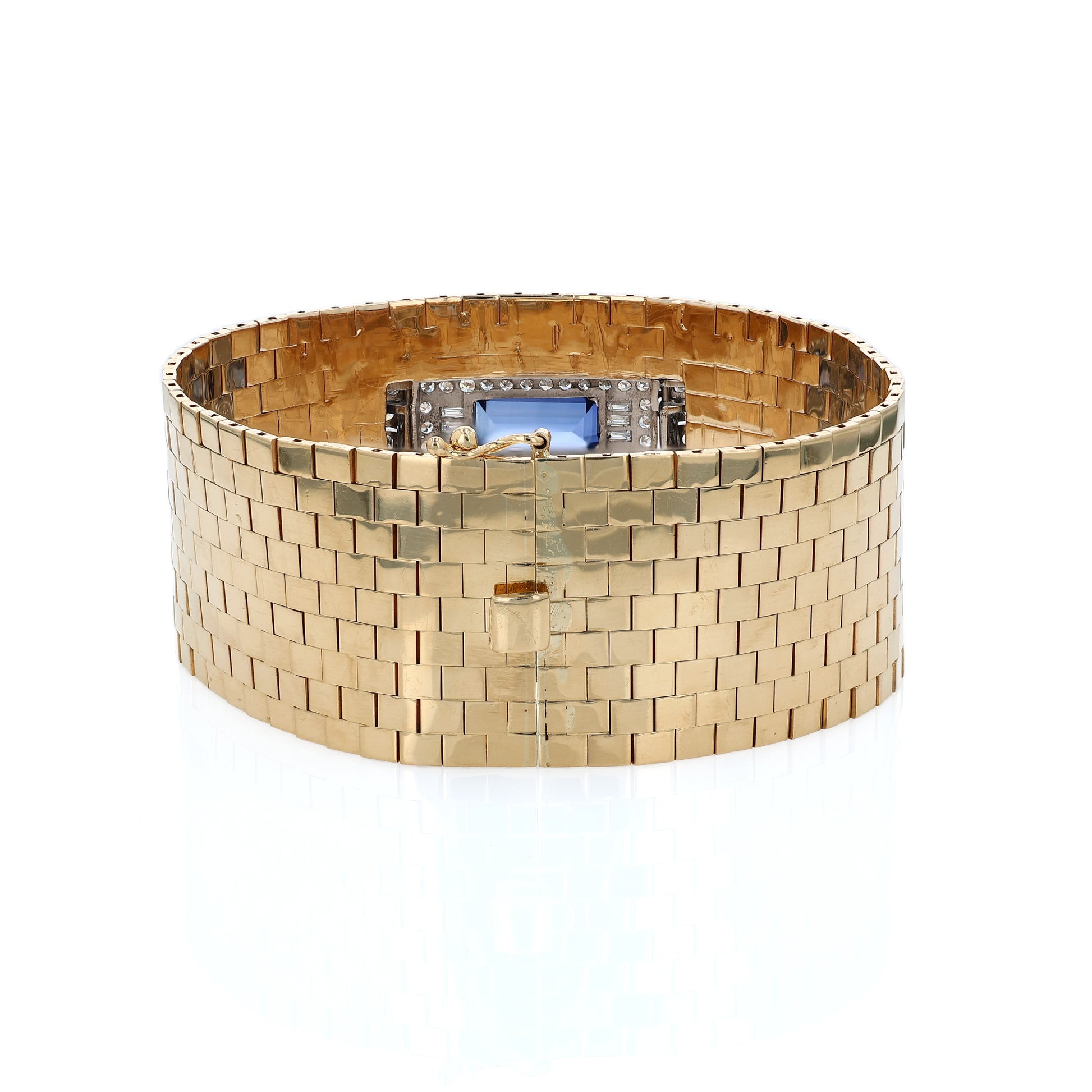 Yellow gold polished wide link design cuff bracelet with a diamond and synthetic sapphire center on a white background