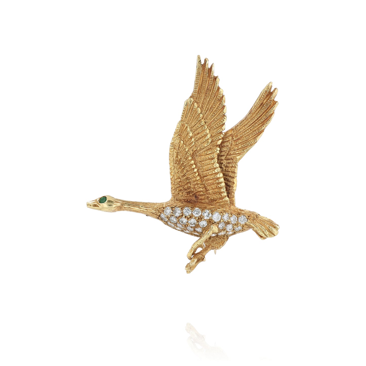 Brushed yellow gold pin of a flying duck with an emerald eye and diamond body on a white background