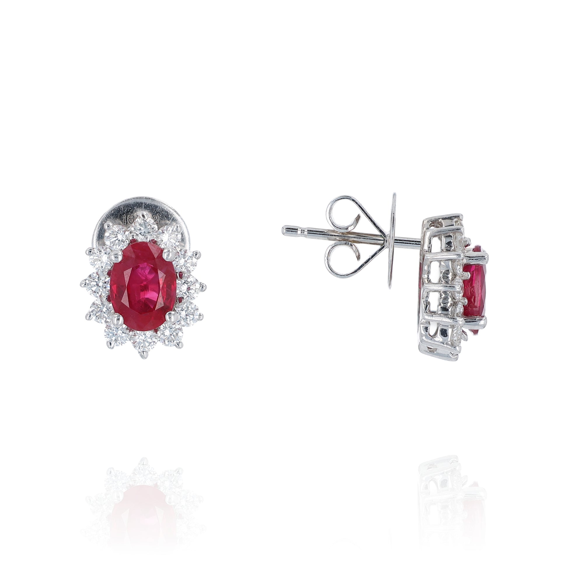 Pair of white gold diamond halo earrings with oval ruby centers on a white background