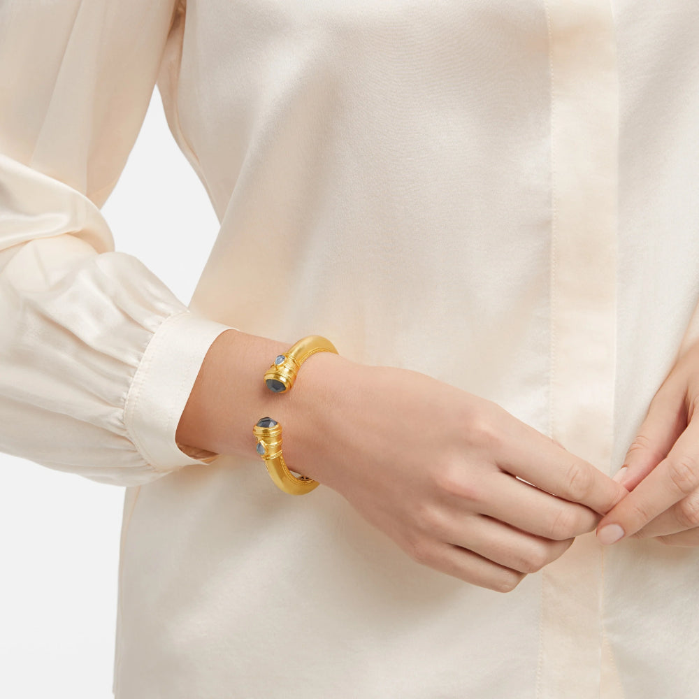 Gold bracelet on a wrist with a plain background