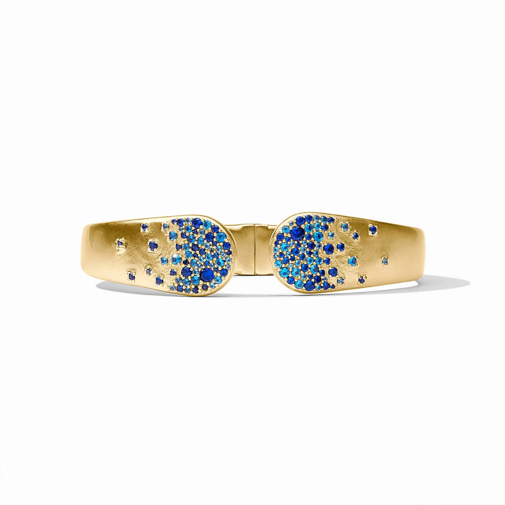 A gold bangle bracelet with two oval pavé-set sections featuring blue and white stones, photographed on a clean white background.