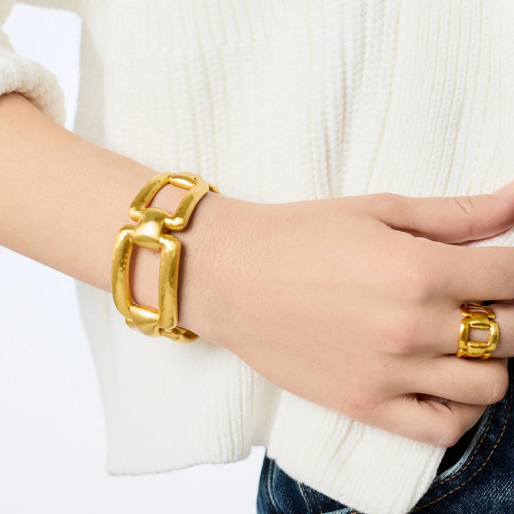 Gold bracelet and ring on a person wearing a white sweater