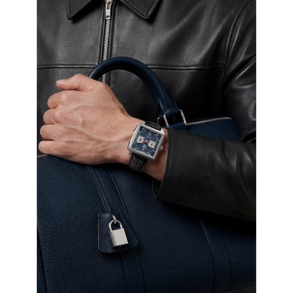 Person wearing a watch with a dark blue leather bag and jacket.
