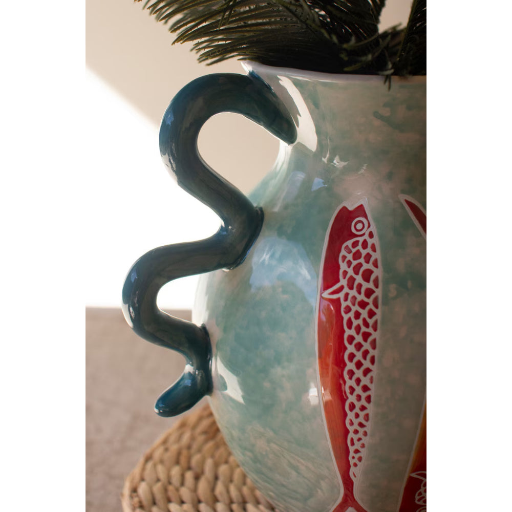 Decorative vase with fish design and hook on a neutral background