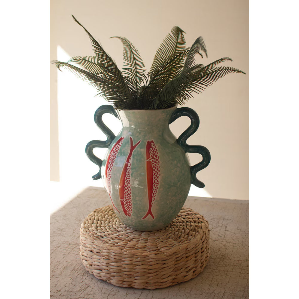 Decorative vase with fish design on a woven surface