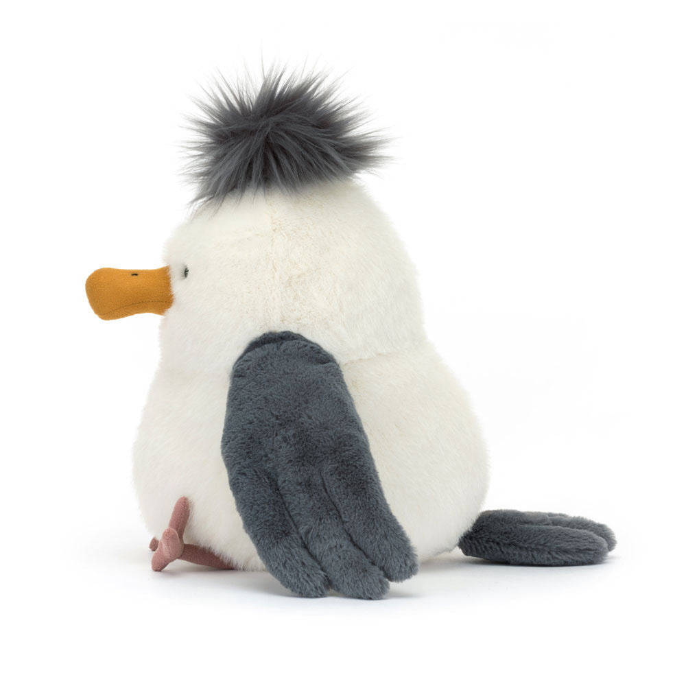 A side photo of a plush toy penguin with a white body, gray wings, and an orange beak on a white background