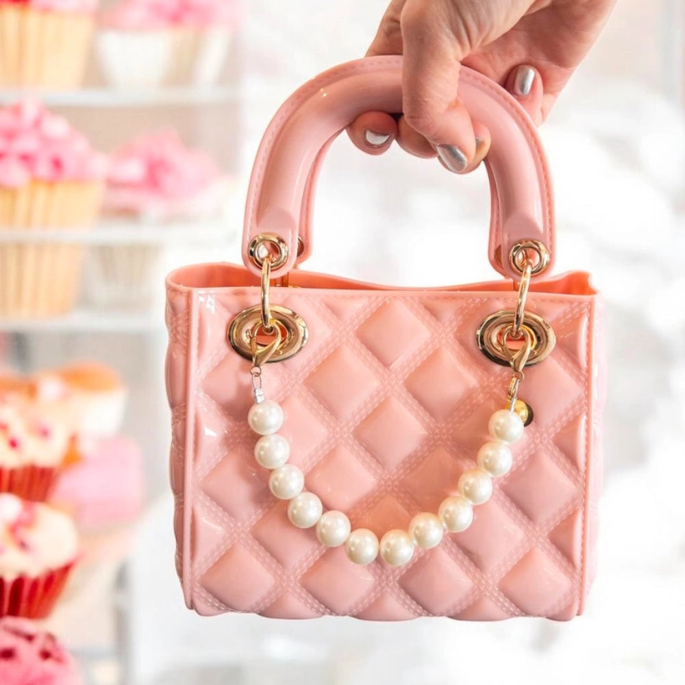 A quilted ballet pink handbag with a matching cross-body strap and attached white pearls