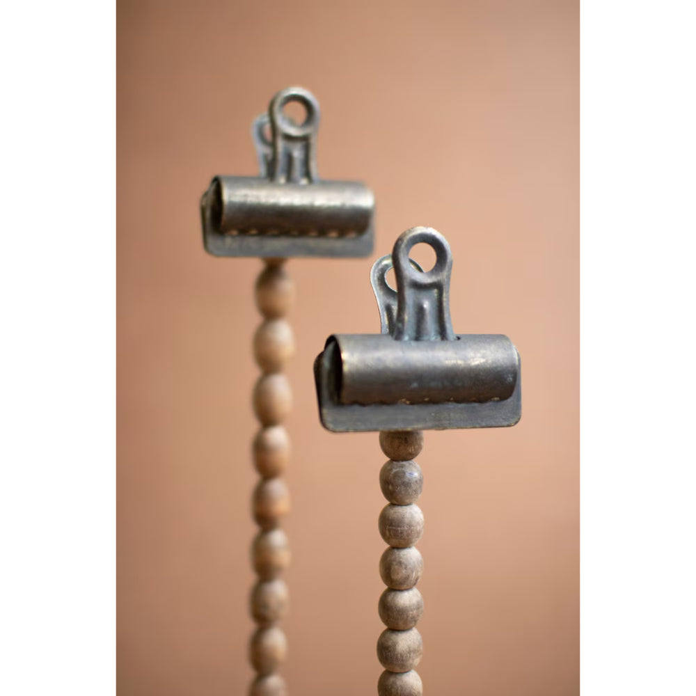 Two metal clips with wooden beads on a blurred background