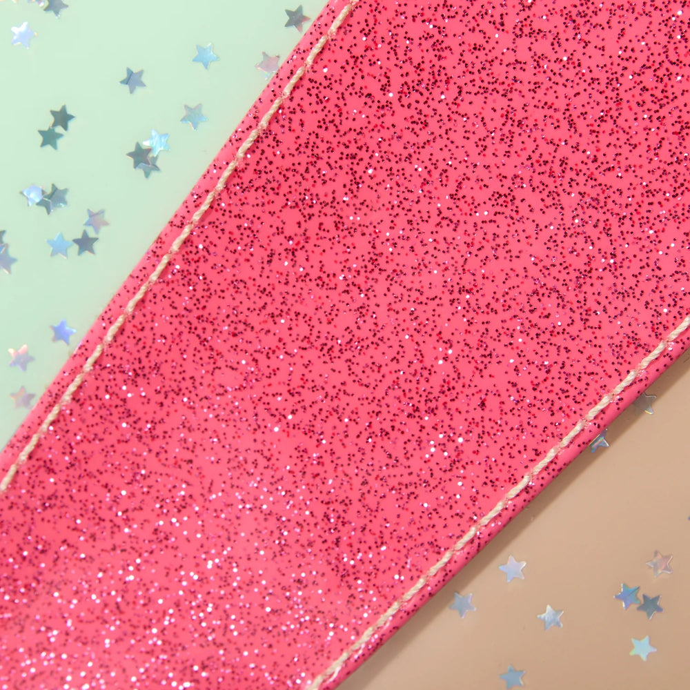 Close-up of a pink glittery material with a beige and light green background with star shapes.