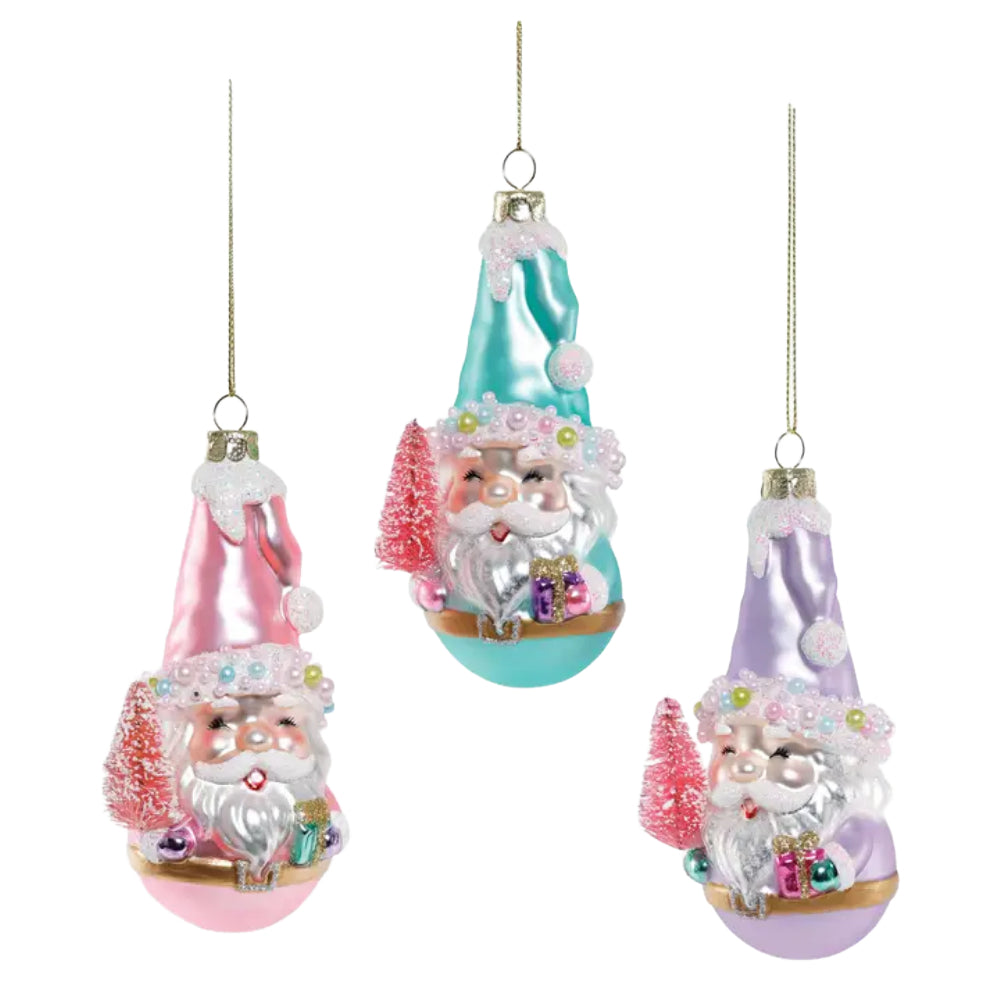 Three hanging Christmas ornaments shaped like Santa in pointed hats, shown on a plain light background. The left ornament is pink, the center one is aqua/turquoise, and the right one is lavender, each with white beard details, small pink trees, and gift accents.