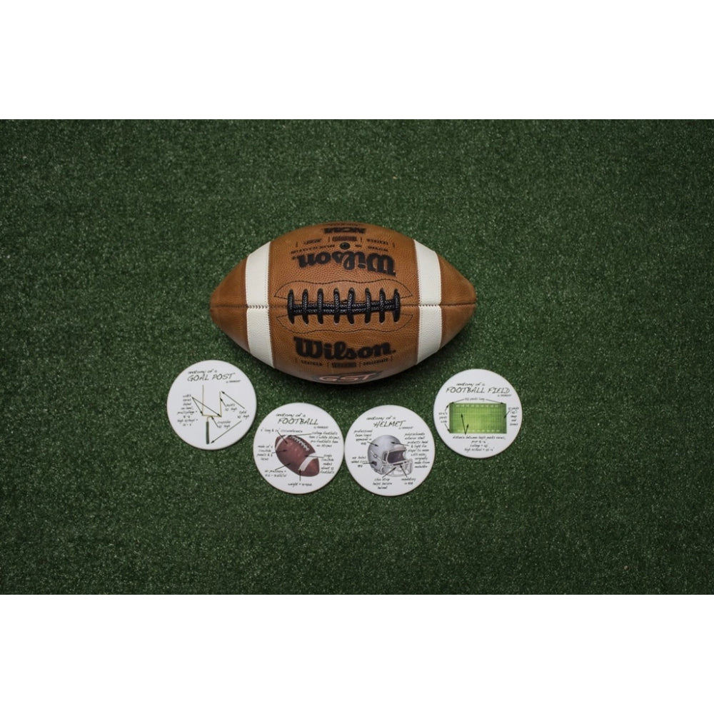 A brown and white Wilson football placed on green turf, with four round printed football-themed coasters or tokens arranged in front of it.