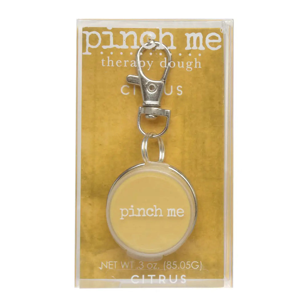 Pinch Me Therapy Dough in Citrus, a round pale yellow disc with a silver metal rim and clasp, packaged in a clear plastic sleeve with a textured gold backing card.