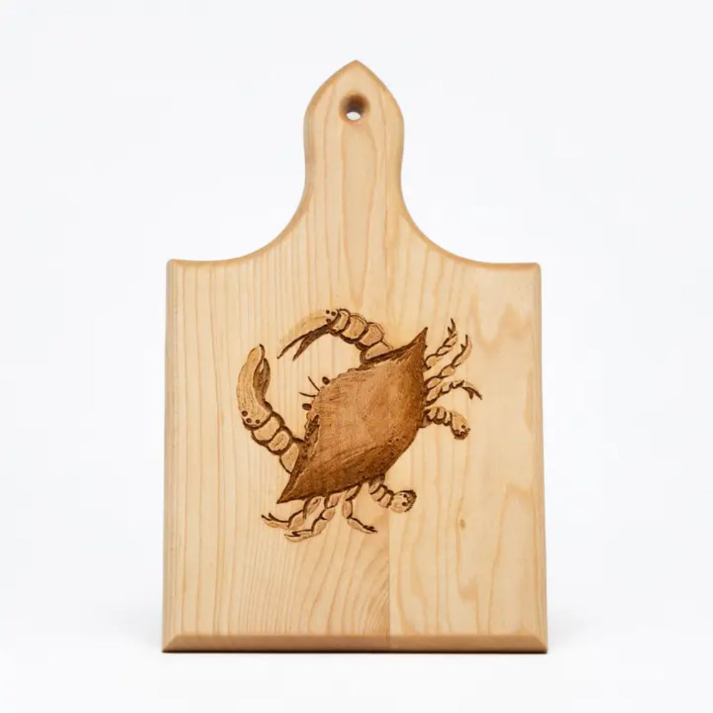 A rectangular wooden cutting board with a handle and a hanging hole, featuring a brown engraved crab design in the center, shown on a plain white background.