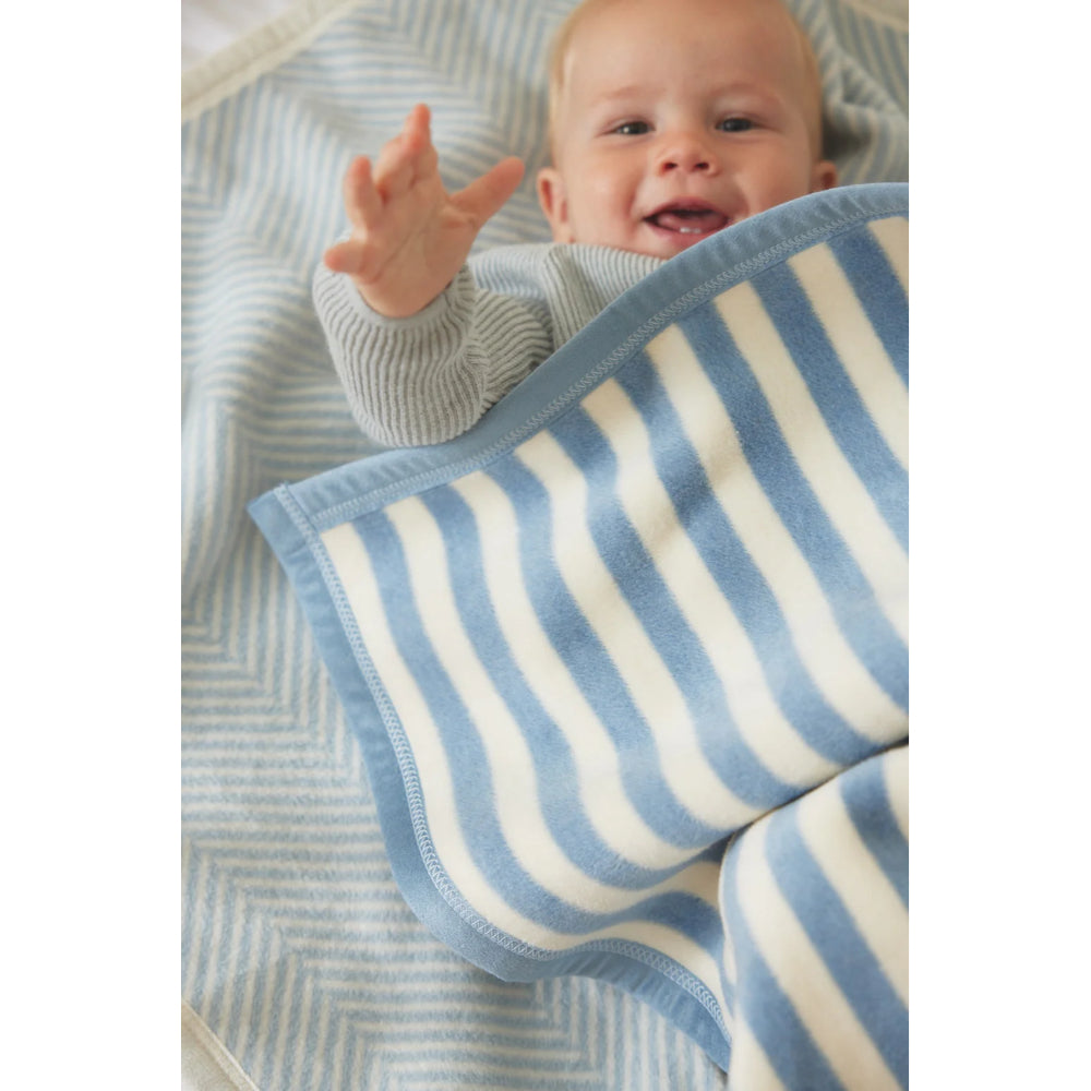 Baby wrapped in a blue and white striped blanket on a blanket surface