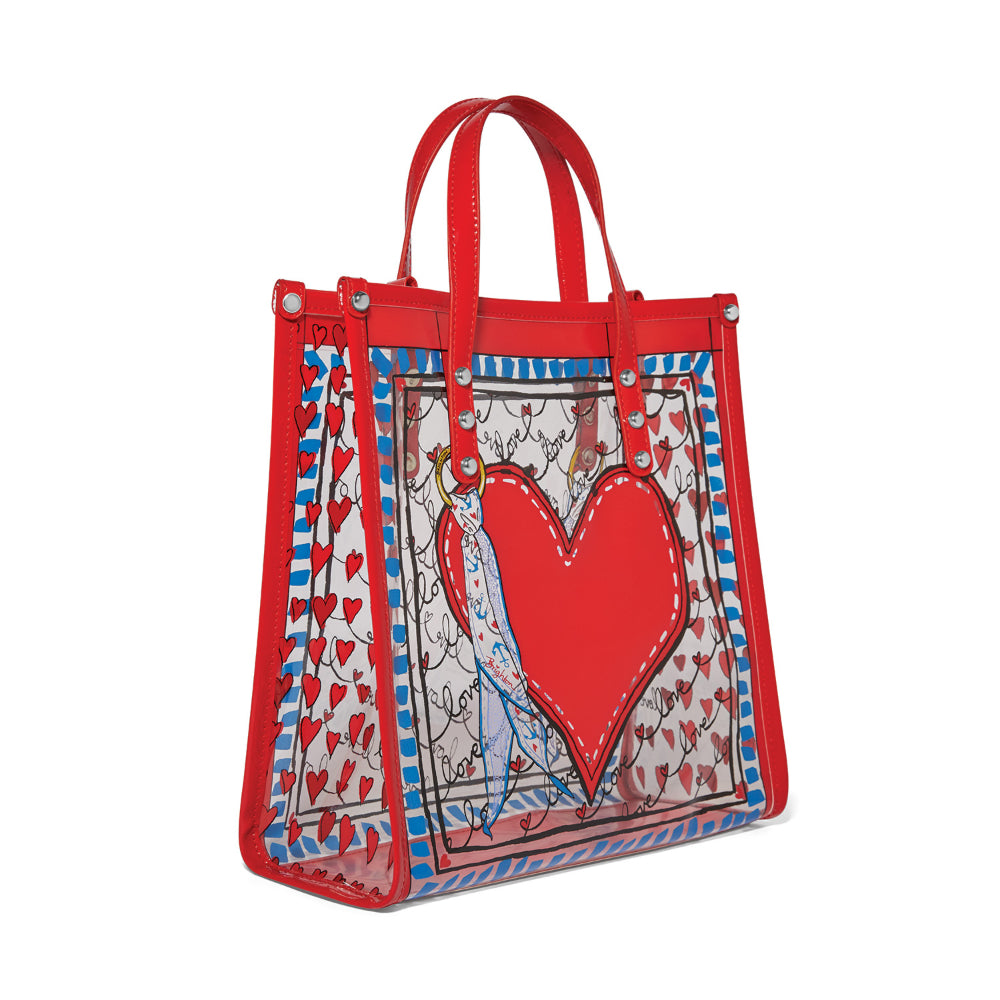 A angled side photo of a red & clear tote bag with a red heart design on a white background.