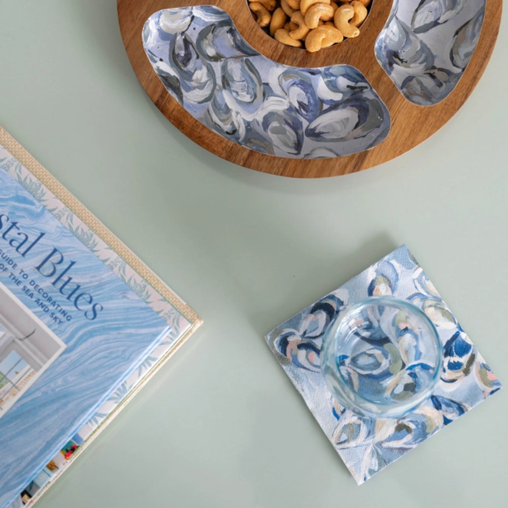 Decorative coasters with blue and white patterns on a light green surface, next to a book titled 'Nautical Blues'.