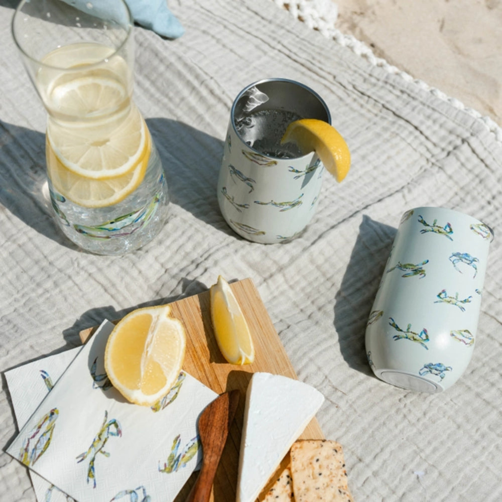 Two glasses with lemon slices, a wooden board with lemon wedges, and patterned coasters on a textured surface.